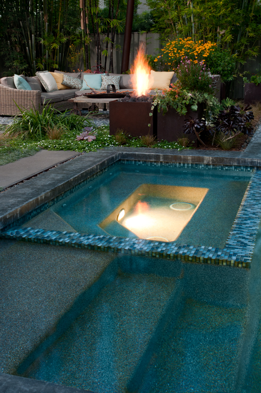 Rusted fire troughs illuminate the garden at night