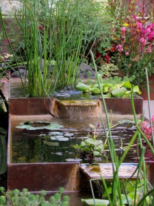 A naturally rusted steel water feature draws attention in this garden